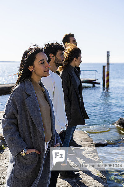 Vier Freunde stehen am Gardasee und schauen auf die Aussicht  Italien