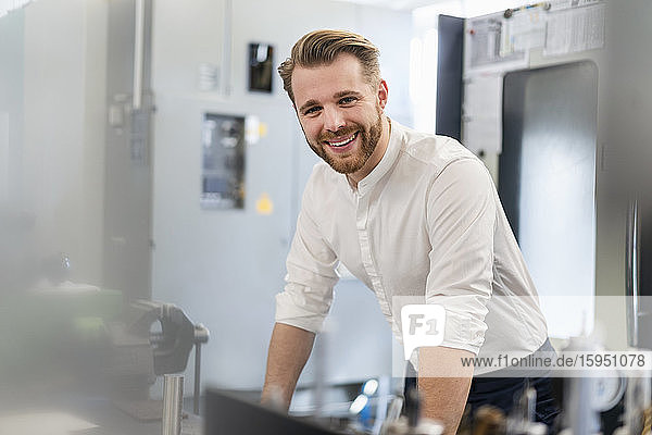 Porträt eines glücklichen jungen Mannes in einer Fabrik