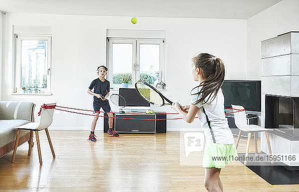 Bruder und Schwester spielen zu Hause Tennis  während sie während der Quarantäne Sport treiben