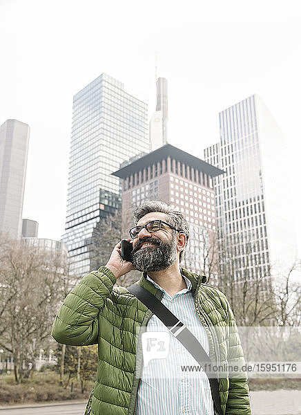 Mann am Telefon vor Wolkenkratzern  Frankfurt  Deutschland