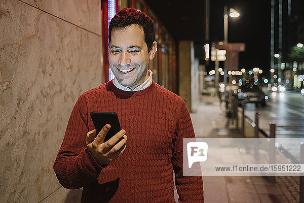Portrait of happy entrepeneur in the city looking at cell phone  Frankfurt  Germany