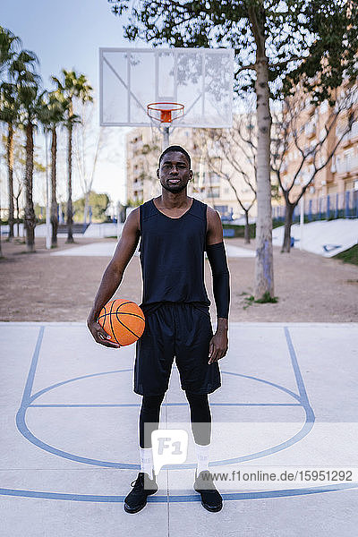 Young man holding basketball on basketball court