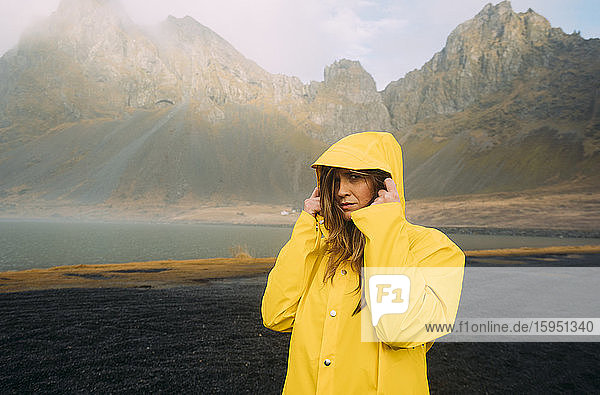 Portrait of woman wearing yellow coat standing at beach in Hvalnes Nature Reserve Beach  Iceland