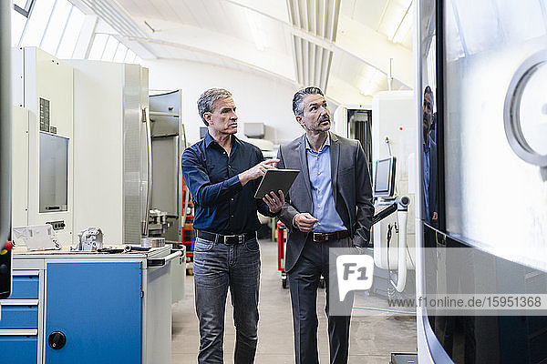 Businessmen in factory  having a meeting  using digital tablet