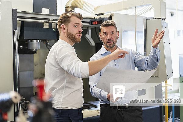 Two men discussing a plan in a factory