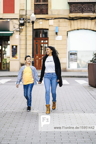 Glückliche Mutter geht Hand in Hand mit ihrem Sohn auf der Straße