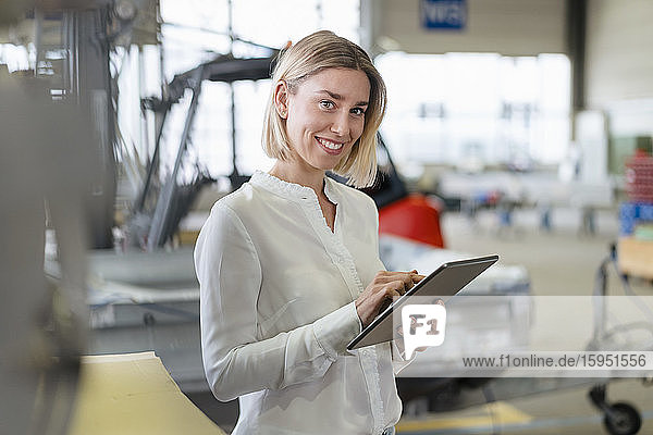 Portrait of smiling young woman using tablet in a factory
