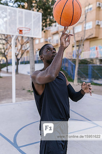 Junger Mann balanciert Basketball auf seinem Finger