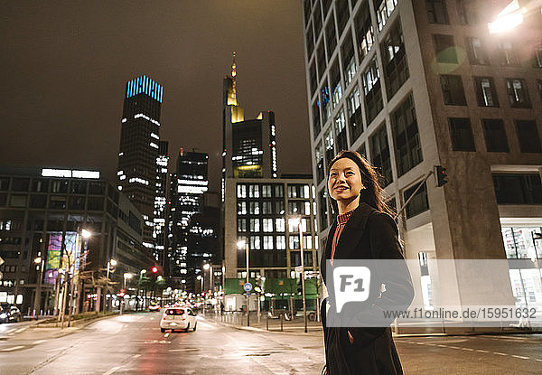 Junge Frau  die nachts in der Stadt die Straße überquert  Frankfurt  Deutschland