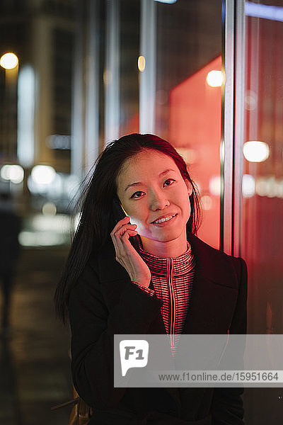 Young woman on the phone in the city at night