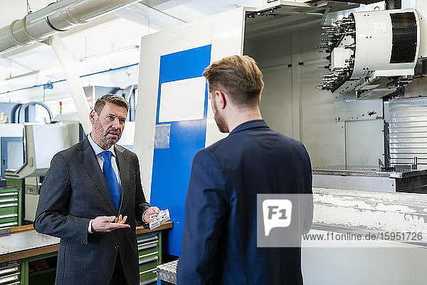 Two businessmen having a work meeting in a factory