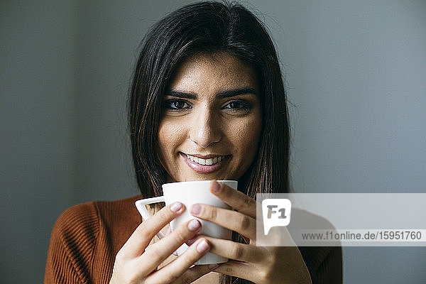 Porträt einer lächelnden Geschäftsfrau  die in der Pause im Büro Kaffee trinkt