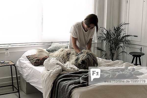 Glückliche reife Frau kuschelt ihren Hund auf dem Bett