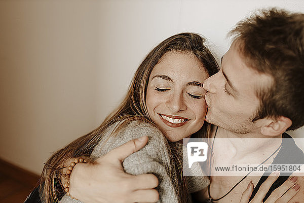 Happy young couple hugging and kissing at home