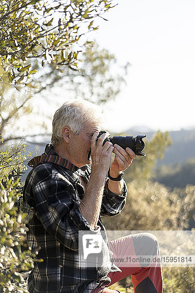 Senior man photographing in nature