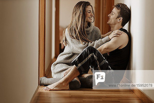 Glückliches junges Paar sitzt zu Hause auf dem Boden