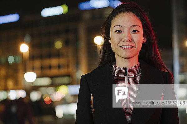 Portrait of a confident young woman in the city at night  Frankfurt  Germany