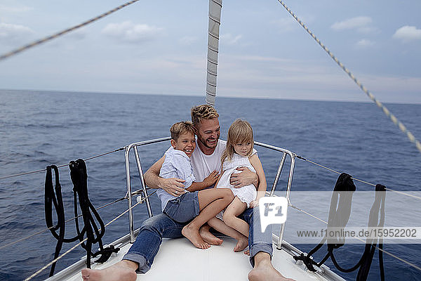 Father with his children sitting on boat deck during sailing trip