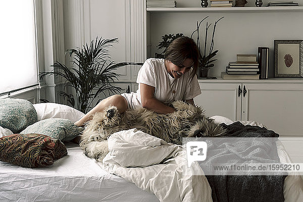 Reife Frau kuschelt ihren Hund auf dem Bett