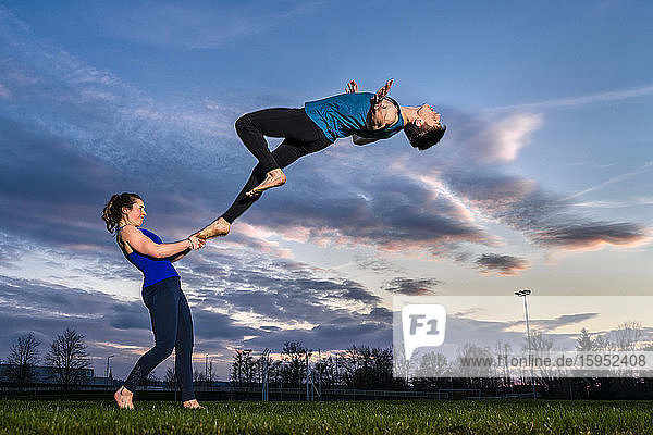 Junges Paar macht bei Sonnenuntergang Akrobatik
