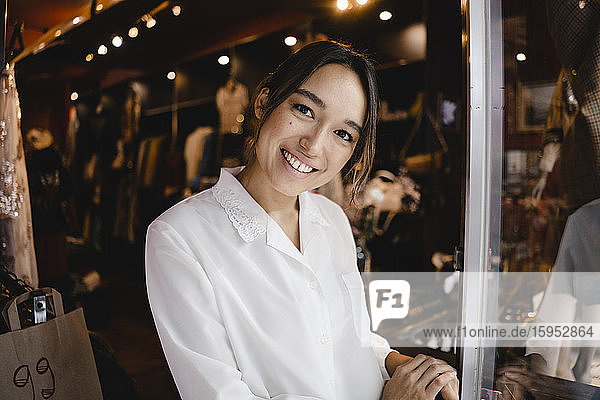 Portrait of confident smiling entrepreneur standing at entrance of store