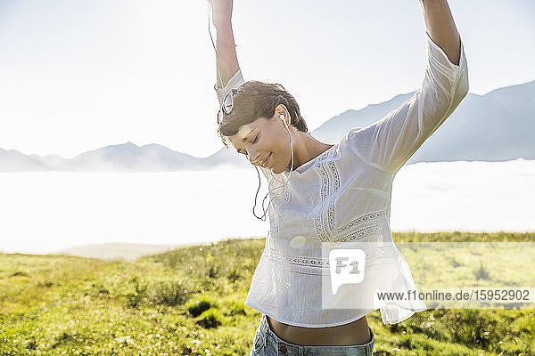 Happy woman listening to music on a meadow in the mountains  Achenkirch  Austria