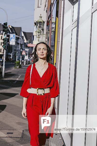 Porträt einer Frau in rotem Kleid beim Spaziergang durch die Stadt
