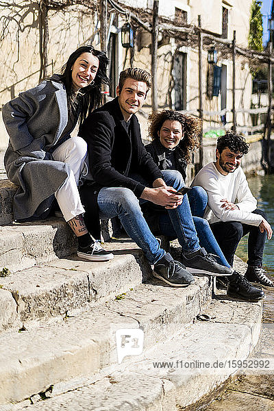 Portrait of four friends sitting on stairs at Lake Garda  Italy