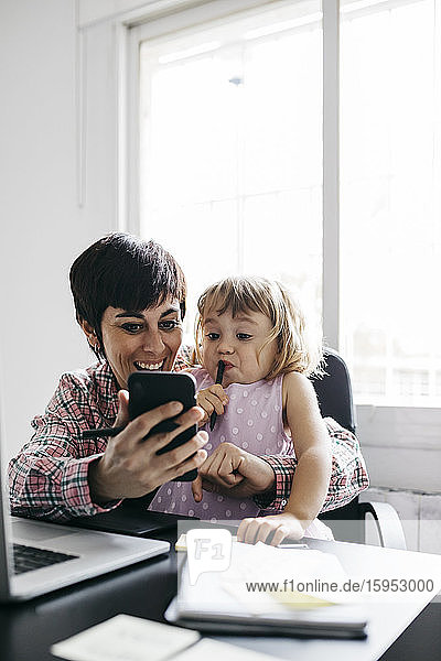 Mutter und Tochter benutzen zu Hause ein Smartphone