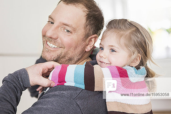 Vater kuschelt mit seiner Tochter zu Hause