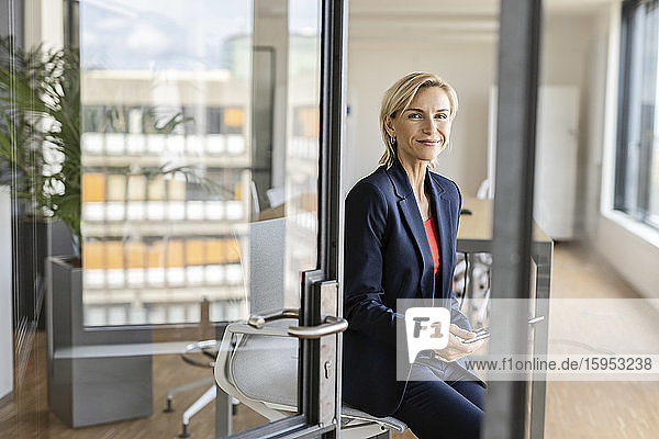 Portrait of blond businesswoman holding tablet in conference room