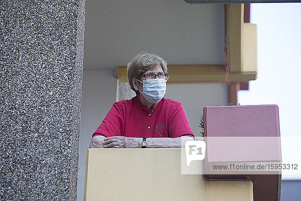 Ältere Frau mit Maske auf dem Balkon  Altersheim