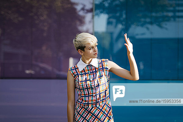 Porträt eines weiblichen Teenagers in farbigem Kleid mit mehrfarbiger Glaswand im Hintergrund
