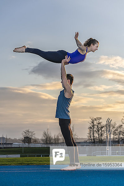 Young couple doing acrobatics at sunset