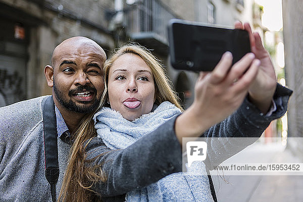 Porträt von Gesichtern  die sich beim Selbermachen mit dem Smartphone verkuppeln  Barcelona  Spanien