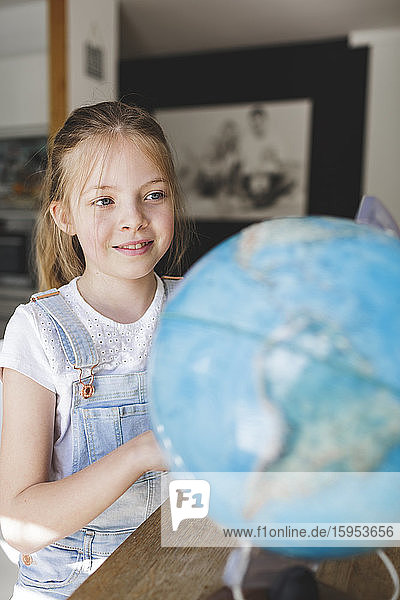 Porträt eines lächelnden Mädchens beim Blick auf den Globus