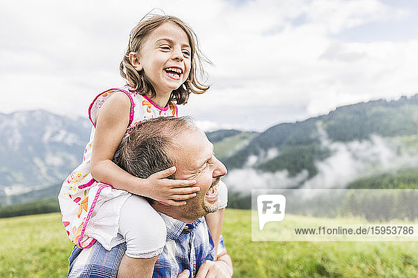 Happy father carrying daughter on shoulders on a meadow in the mountains  Achenkirch  Austria