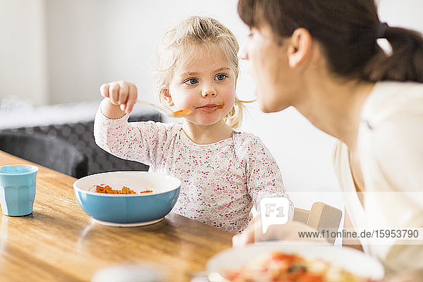 Tochter füttert Mutter mit Löffel zu Hause
