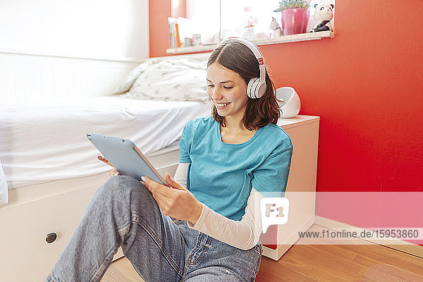 Porträt eines lächelnden Teenagers mit Kopfhörer und digitalem Tablet  der zu Hause lernt