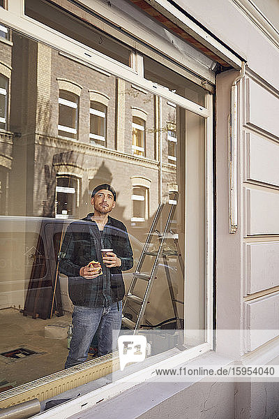 Mann renoviert Ladenstandort  trinkt Kaffee  schaut aus dem Fenster