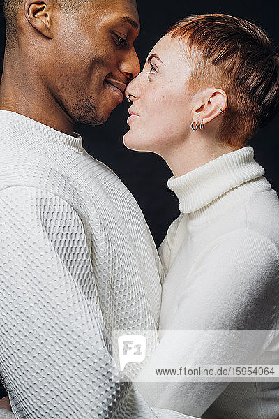 Studio portrait of affectionate mixed race couple face to face