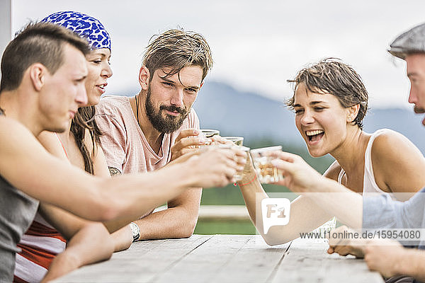 Freunde sitzen an einem Holztisch in den Bergen und trinken Gläser  Achenkirch  Österreich
