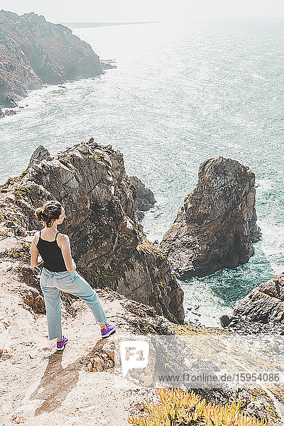 Portugal  Bezirk Lissabon  Sintra  Junge Frau bewundert den Atlantischen Ozean vom Rand der Klippen von Cabo da Roca