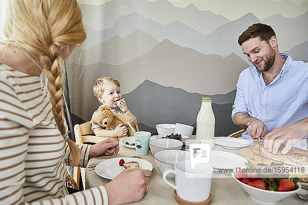 Porträt eines kleinen Jungen  der mit seinen Eltern am Frühstückstisch sitzt