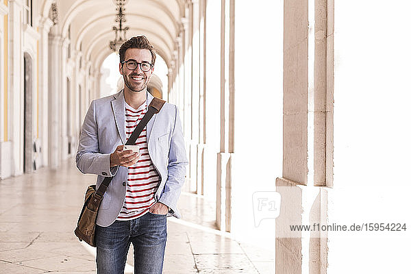Porträt eines lächelnden jungen Mannes mit Smartphone in der Stadt  Lissabon  Portugal