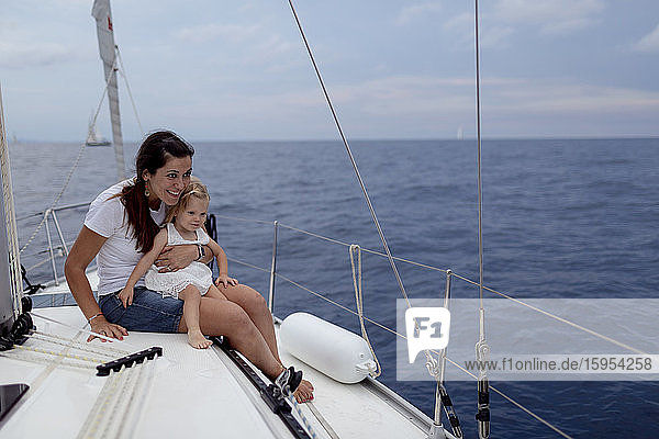 Mother and her daughter sitting on boat deck during sailing trip