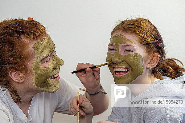 Bruder trägt Gesichtsmaske auf das Gesicht seiner Schwester auf