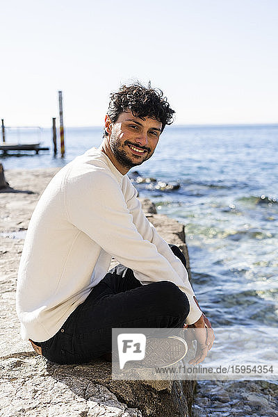 Portrait of smiling young man sitting at Lake Garda  Italy