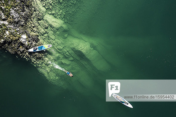Germany  Bavaria  Aerial view of two paddleboarders relaxing on green shore of Lake Walchen