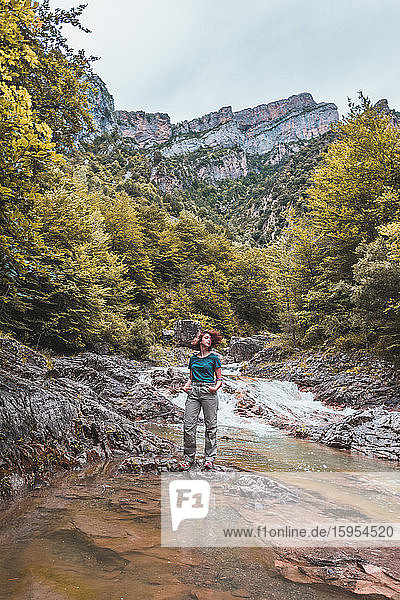 Spanien  Provinz Huesca  Porträt einer Wanderin  die über einem klaren Bergfluss posiert